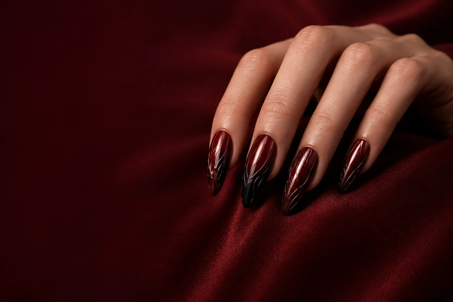 Burgundy sculpted press-on nail art worn on a hand in an editorial atmosphere study